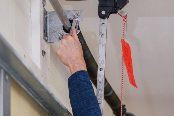 Man repairing electric garage door coiled tension spring. Instal